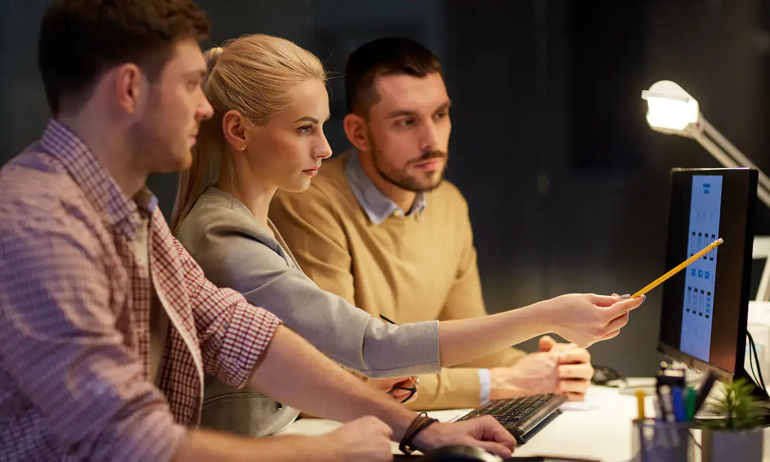 Bowling team reviewing scores on a computer screen at NeoBowling.