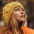A young woman with red hair wearing a yellow knit hat outdoors in autumn.