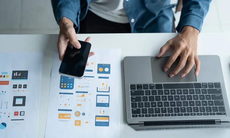 Analyzing data and planning digital marketing strategies using a smartphone and laptop.